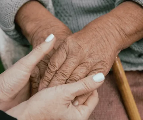 Caregiver gently holding an older adult's hands